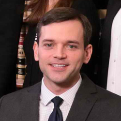 A man in suit and tie standing next to other people.