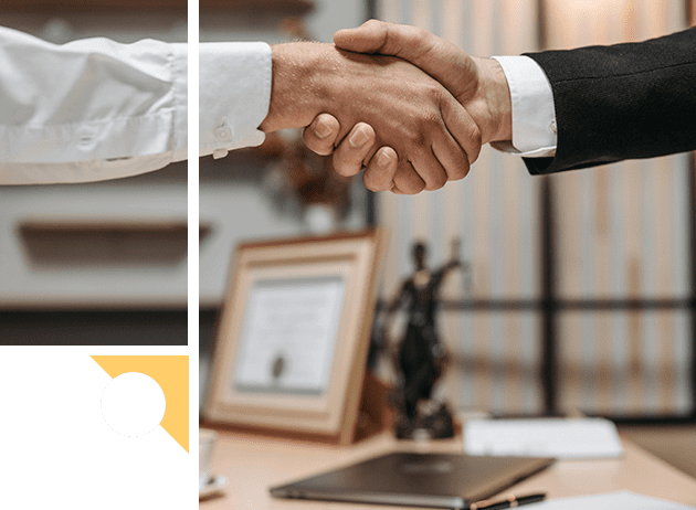 Two people shaking hands over a desk.