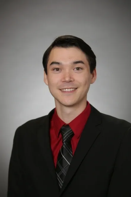 A man in a suit and tie smiling for the camera.