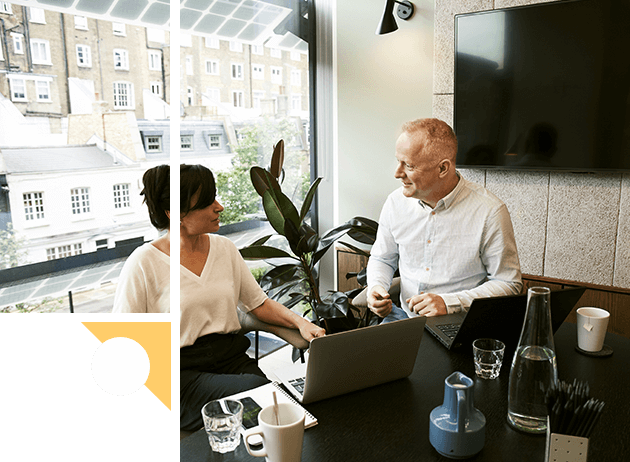 A man and woman sitting at a table with a laptop.